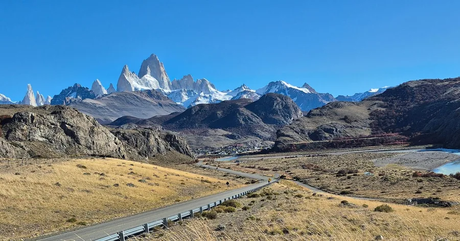 Der Mount Fitz Roy und seine verschneiten Nachbarn über der braunen patagonischen Steppe unter blauem Himmel
